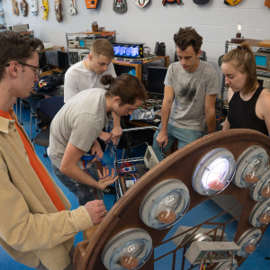 A group of students working on a machine in a lab