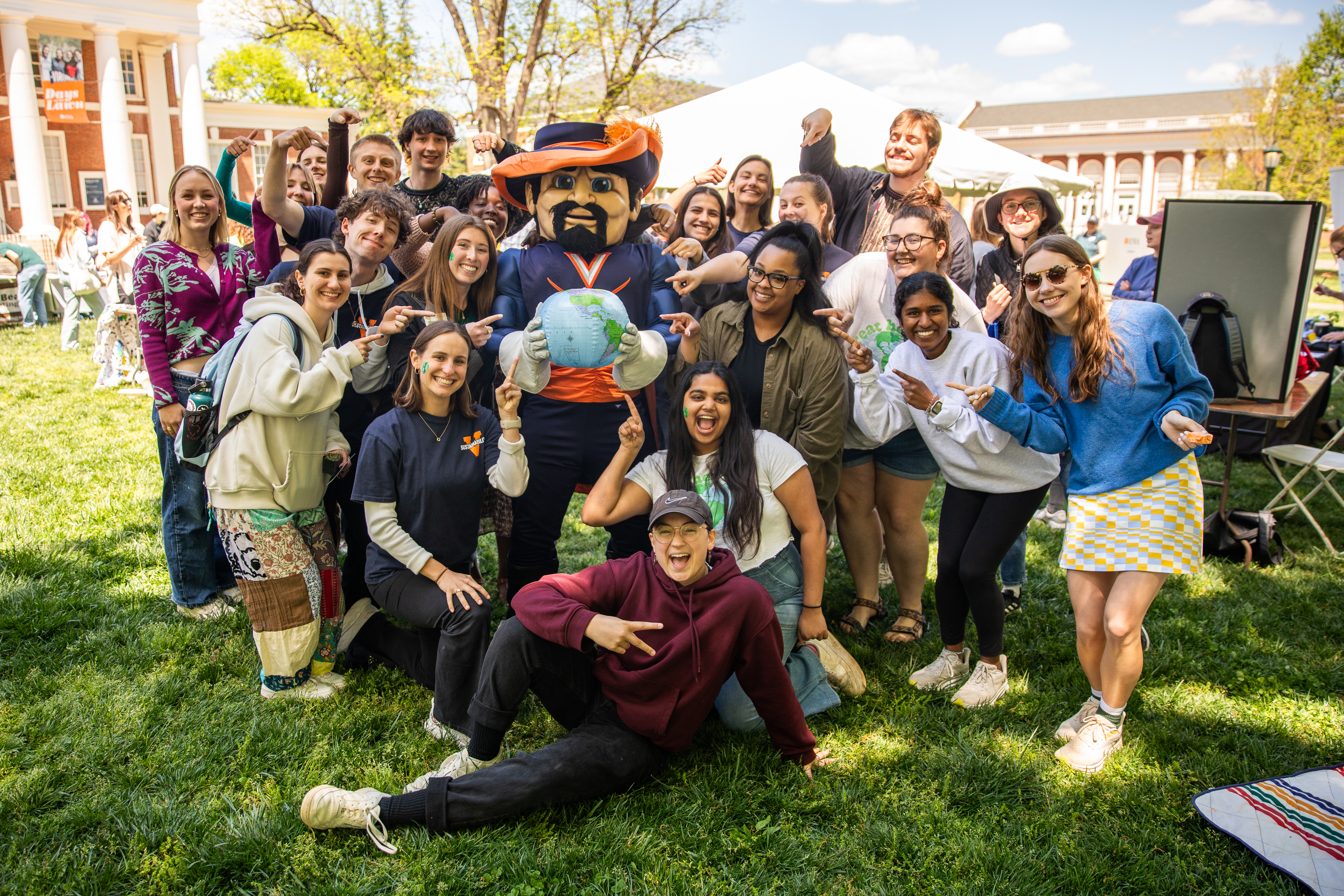 Group photo of students with Cav Man holding a globe on the lawn