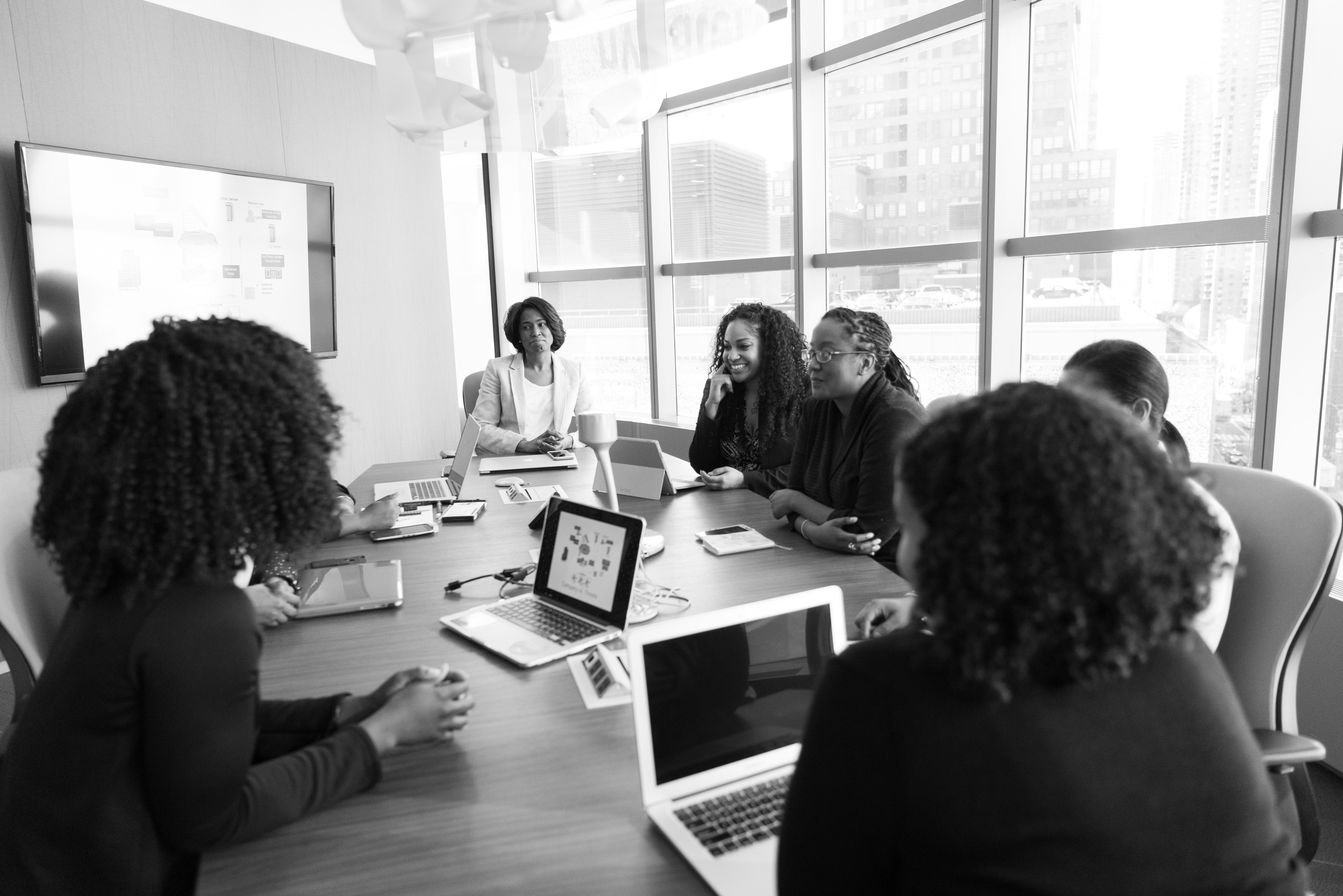 Eight people sitting around conference table beside window