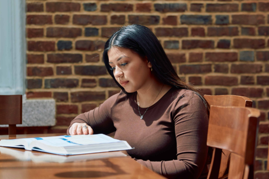 Student studying at a desk in front of a brick wall