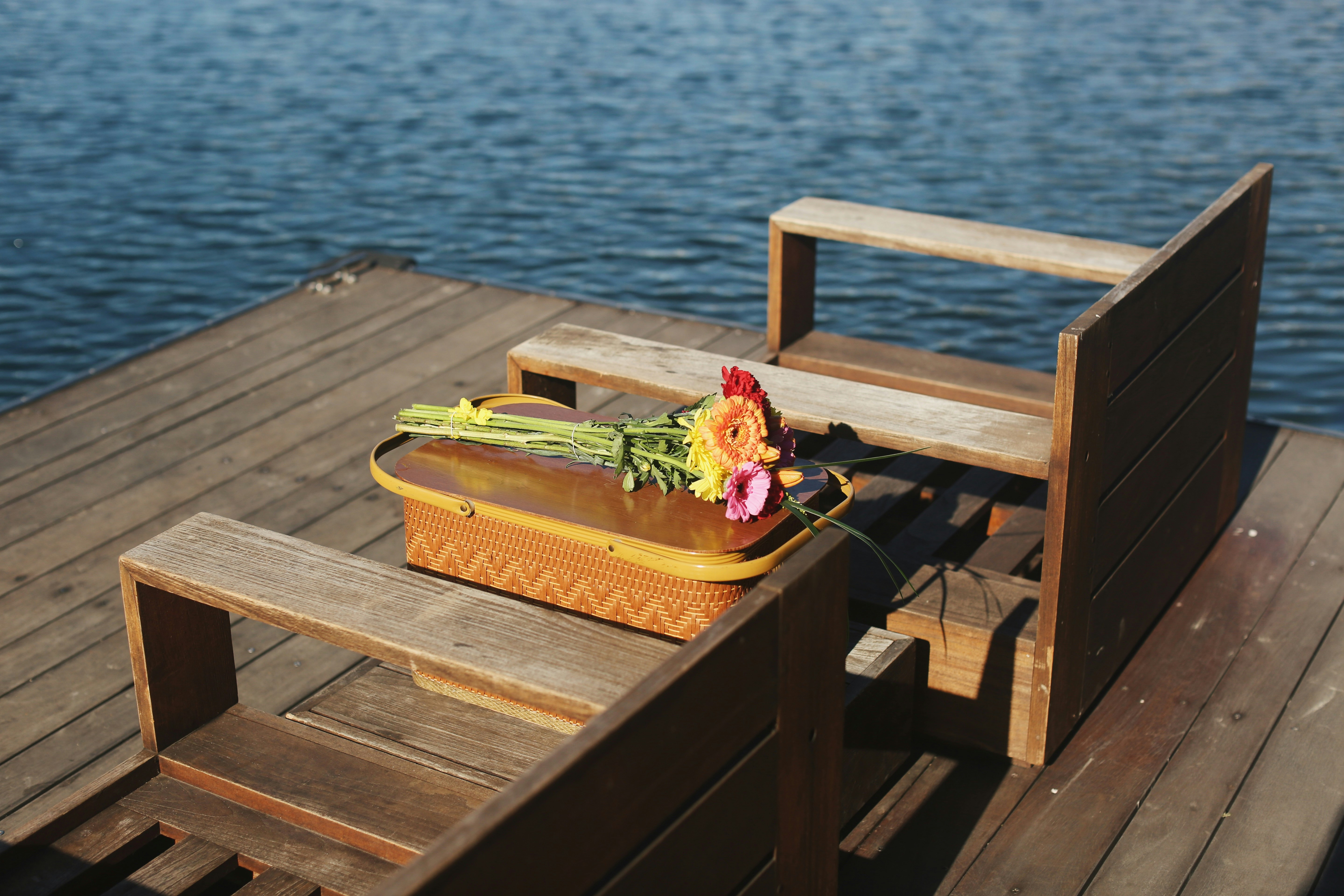 Basket, flower bouquet, and two empty chairs on a pier