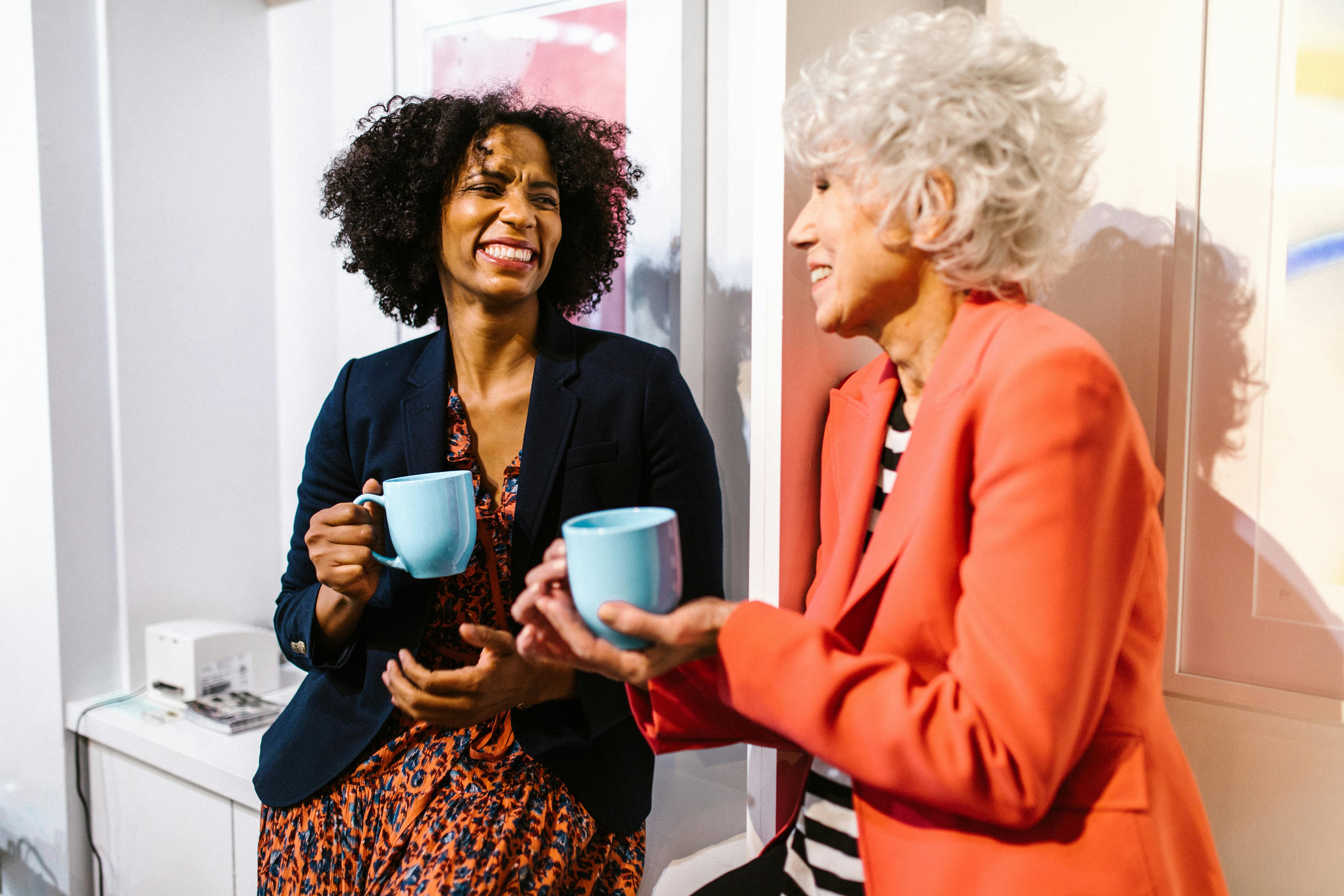 Two women laughing and holding blue mugs