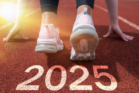 Feet, in sneakers, and hands in the start position on a track marked 2025